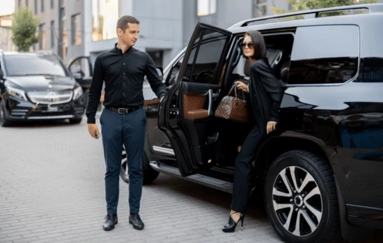Chauffeur opening door of a SUV for a female passenger