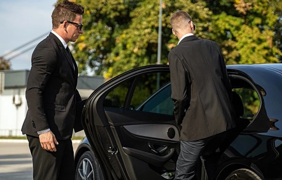 Chauffeur opening the door of a black town car for the client